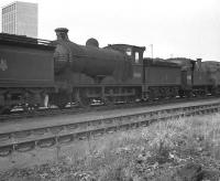 A line of <I>stored</I> locomotives, including 64466 and 69012, stand in the sidings at Thornton Junction MPD in the 1960s, with one of the towers enclosing the headgear of Rothes Colliery in the background.<br><br>[K A Gray //]