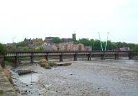 Formerly an overhead electrified rail route, Greyhound Bridge on the other Lancaster to Morecambe line closed to trains in 1966 and was soon converted for road traffic. This view from the site of Lancaster Green Ayre station, alongside the River Lune (at low tide), also shows the Castle and the Priory church on the hill behind. <br><br>[Mark Bartlett 24/04/2009]