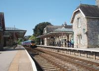 A sizeable group of passengers waits for the first eastbound service of the day on a sunny Sunday morning at Grange-over-Sands. Unusually, due to engineering work, Transpennine 185130 is heading for Manchester Victoria rather than the Airport.<br><br>[Mark Bartlett 26/04/2009]