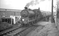 View north as class J37 no 64587 stands at Pomathorn at the head of the SLS <I>Farewell to Peebles</I> railtour on 3 February 1962, with the locomotive straddling the level crossing over the B6372. The imposing building in the background is the former Pomathorn paper mill, currently (2009) in use as a storage facility. Pomathorn station closed in 1962 and is now a private house [see image 6277].  <br>
<br><br>[K A Gray 03/02/1962]