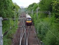 View west along the line running parallel with Kennedy Drive (behind the trees to the left) in Airdrie on 27 May 2009, as 320301 approaches Airdrie Station.<br><br>[John Steven 27/05/2009]