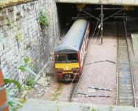 Photograph taken through a convenient hole in a fence as 320312 arrives eastbound into GlasgowQueen Street Low Level on 16 June 2009.<br>
<br><br>[Brian Smith 16/06/2009]
