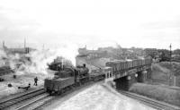 Ivatt class 2MT 2-6-0 no 46455 brings a freight out of Crown Street goods depot, Carlisle, in July 1958 across a double track bridge spanning 3 sets of lines. Those nearest are the goods lines from Upperby, in the centre are those from London Road and furthest away are the N&C/S&C passenger lines into Citadel station. The WCML can be seen on the extreme left of the picture. Although best known as a goods depot, Crown Street began life in 1844 as the site of the passenger terminus of the Maryport & Carlisle Railway, a function it performed for only 5 years, following which trains switched to Citadel. Crown Street goods depot lasted much longer however, being officially closed as such in 1966, although most of the track had been lifted the previous year. The deck of the bridge in the photograph had been removed by 1971. [See image 5345]  <br>
<br><br>[Robin Barbour Collection (Courtesy Bruce McCartney) 05/07/1958]