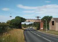 One of the aerial ropeways serving Claughton brickworks still operates from the claypits on Claughton Moor. The other was dismantled in the 1990s. This is the final bit of the ropeway where the buckets cross the A683, drop into the wheelhouse and discharge their load of clay. View towards Lancaster. The Lancaster to Wennington railway was behind the brickworks and the trackbed runs very close to the A683 both sides of Claughton village. Map Ref SD 563664. <br><br>[Mark Bartlett 14/06/2009]
