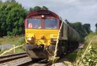 EWS 66100 heads empty tankers from the BP terminal at Dalston, Cumbria, on 22 July 2009, bound for the Grangemouth refinery. The train is seen here approaching Low Mill level crossing near the start of its journey north.<br>
<br><br>[Brian Smith 22/07/2009]