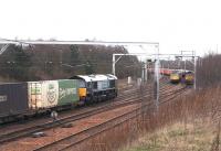 DRS 66412 with a container train bound for Grangemouth heads north from Carstairs on 8 March 2007, having travelled via Edinburgh and the ECML. The train is about to pass Freightliner class 86 locomotives 86610+86612 on the Coatbridge - Basford Hall containers, which in turn is in the process of overtaking an EWS class 66 held at a red light with a consignment of coal from nearby Ravenstruther destined for Drax power station.<br><br>[John Furnevel 08/03/2007]