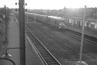 Glasgow Fair Monday in July 1966 sees an EE type 1 carrying an express passenger headcode running through the Glasgow bound platform at Hillington West with a special. Note the old platform buildings still in place at this time.<br>
<br>
<br><br>[Colin Miller /07/1966]