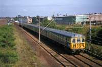 Two almost new Class 312 EMU sets seen just after passing Colchester Hythe station in August 1977 on a Liverpool Street to Walton (front unit) and Clacton (rear unit) working. While the line remains, virtually every other part of this scene has been transformed. The Colchester Lathe company on the right is long gone (inevitably replaced by a Tesco car park and Superstore), a road bridge has been built across the foreground to bypass the level crossing seen in the distance, and huge blocks of commuter flats have arisen on the left.<br><br>[Mark Dufton 27/08/1977]