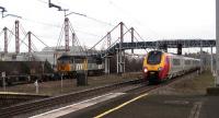 Fastline 56302 with a rake of container flats is 'stuck' on the 'slow line' eastbound at Birmingham International on 29 November 2006 as a Virgin Voyager arrives with a westbound cross country service. One of the halls of the NEC can be seen on the left behind the Class 56 loco.<br><br>[John McIntyre 29/11/2006]