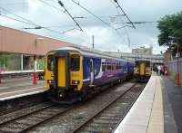 A sizeable complement of passengers waiting for the guard to open the doors of single car 153378 on a Millom service in Platform 1 at Lancaster.  Alongside, in bay Platform 2, 156423 waits to leave for Morecambe.<br><br>[Mark Bartlett 22/07/2009]