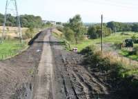 Looking east from Katherine Park Lane bridge on the eastern edge of Airdrie along the trackbed towards Bathgate on 11 September 2009. The route of the former Moffat Mills branch, latterly serving Inverhouse distillery, can be seen turning south where the oil drums now stand. [See image 24624]<br><br>[John Furnevel 11/09/2009]