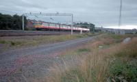 In 1987 an eastbound service from Paisley Gilmour Street station has just passed Wallneuk Junction. In the foreground are the remains of the line to Greenlaw Goods and Renfrew (nearest to camera) both of which had been lifted the previous year. The open line here is due to be quadrupled right through to Arkleston Junction despite the cancellation of the Glasgow Airport Rail Link.<br><br>[Ewan Crawford //1987]