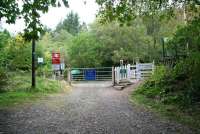 The road to Achnashellach station - part 2. The level crossing reached via the unclassified road running north from the A890 [see image 25649], seen here on 27 September with the entrance to the platform on the right. The green umbrella on the other side of the crossing stands at the entrance to the drive of the former station master's house (shown in image 25641) where tea, coffee and other refreshments are now available.<br><br>[John Furnevel 27/09/2009]