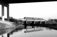 The 1320 Manchester Victoria to Southport crosses the River Douglas and the Leeds & Liverpool Canal immediately west of Gathurst station. The three-car BRCW Class 104 DMU is also about to pass under the M6 Motorway.  These Newton Heath sets were the mainstay of services to Blackpool and Southport for around 25 years.<br><br>[Mark Bartlett 28/11/1978]