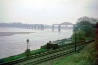 The Severn and Wye Railway crossed the river Severn and ran through Lydney and Cinderford in the Forest of Dean to join the GWR at Lydbrook Junction on the river Wye. This bridge over the Severn between Sharpness and Lydney was brought down by a drifting boat in 1960. It was finally demolished in about 1967 - completed 1970 - this picture is from 1966. Immediately after the bridge closed, schoolchildren were ferried by rail through Gloucester each day for some months. The line in the foreground is the South Wales Railway.<br><br>[John Thorn //1966]