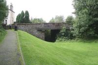 Here stood the basic wooden platforms of St Andrew Street station in Castle Douglas (actually located on Abercromby Road), seen looking south towards Kirkcudbright on 2 September 2009. The site is completely overgrown beyond the bridge, where it now borders the local golf club. The basic facility was opened as a temporary measure by the Kirkcudbright Railway in 1864 due to difficulties with sharing arrangements at the Castle Douglas and Dumfries station (opened 1859). It remained in place for 3 years. Following eventual closure of the line by BR in 1965, this part of the route became a pedestrian shortcut to the town centre (behind the camera).<br><br>[John Furnevel 02/09/2009]