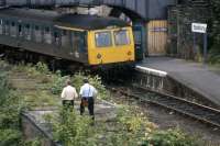 The crew of an afternoon service from Marks Tey has plenty of time for a stroll around the overgrown station at Sudbury before needing to head back on August 10th 1980. The original building survived for a few more years before fire damage and vandalism hastened its demolition. In 1990, the track was slewed over to the right and into a new terminal platform on the site of the former loading dock. [See image 41998] <br><br>[Mark Dufton 10/08/1980]