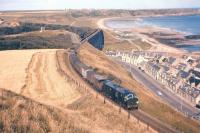 September 1961, in former Great North of Scotland Railway territory. A mixed goods train from Elgin heading towards Aberdeen skirts the Moray Coast town of Cullen, hauled by one of the ill-fated NBL Type 2s built in Glasgow between 1958 and 1960. 58 of the class were constructed, with 20 re-engined between 1963 and 1965 to improve reliability, but all had been withdrawn from service by 1971.<br><br>[Frank Spaven Collection (Courtesy David Spaven) /09/1961]