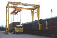 Folowing closure of the Speyside line in 1968, the future (other than a short interlude while coal traffic continued to Aberlour) lay in modern railheads at Dufftown (for grain and coal) and Elgin (for whisky and general freight). At Elgin a new container crane was installed, and here a BR feeder lorry with a whisky 'custom lock' container from Speyside stands beside a Class 24 shunting the ex-GNSR yard.<br>
<br><br>[David Spaven //1968]