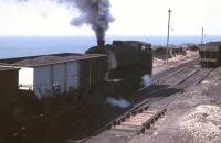 High on the cliffs overlooking the Irish Sea, a Giesl ejector fitted WD 0-6-0ST, probably <I>Revenge</I>, busies itself with loaded 21T coal hopper wagons. This was quite a setting for a coal mine and many of its workings were under the sea. The colliery is now partly preserved as a mining museum. <br><br>[David Hindle //1968]