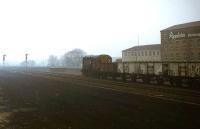 Trip working 9K47 leaves Healey Mills yard on a misty morning in 1979 behind 08098 and heads for Wakefield Wagon shops with wagons for repair. This diagram had originated in steam days and served various locations in the Healey Mills and Wakefield area. Picture taken from the former cattle dock, by then the only surviving remnant of the closed station. With thanks to Wyn Garnett, former Healey Mills shunter, who provided local information and spotted a green repair card on the fourth wagon solebar. [See image 26508]. <br><br>[Mark Bartlett 10/04/1979]