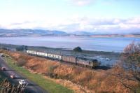 A class 24 locomotive with a short Kyle-Inverness train skirts the south shore of the Beauly Firth between Lentran and Bunchrew as it nears its destination in 1975.<br><br>[Frank Spaven Collection (Courtesy David Spaven) //1975]