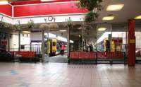 View over the clean and colourful concourse of the 1975 Fort William station looking towards the platforms in the autumn of 2005. A service to Glasgow Queen Street is getting ready to leave platform 1, with a train for Mallaig standing alongside at platform 2.<br><br>[John Furnevel 29/09/2005]