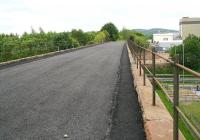 The fenced off deck of Cargenbridge Viaduct, 2 miles south west of Dumfries, seen looking through the railings towards Stranraer in May 2007. The viaduct carried traffic on the <I>Port Road</I> until closure of the line as a through route  in 1965, following which it continued for many years to serve the ICI plant that stood in the right background (much of the area is now a business park). Final closure of this remaining section came in 1994. The <I>Maxwelltown Railway Path</I> now occupies the old trackbed from a point just behind the camera back to Dumfries. (The western access to the path can be seen bottom right.) [See image 15525].<br><br>[John Furnevel 29/05/2007]