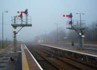 Despite the modern safety rails the bracket semaphores at the North end of Barrow station are still very impressive. Also just visible through the mist is another semaphore, controlling the exit from Platform 3, with the Furness Railway signal box beyond. View west towards Askam on 23 January 2010. [See image 7075] for this view on a clear day. <br><br>[Mark Bartlett 23/01/2010]