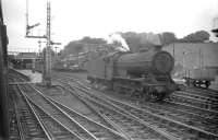 Photograph taken from a train passing south through Alnmouth station on 13 August 1960. Alnmouth was the junction for the Alnwick branch and possessed a 2-road locomotive shed (sub to 52D Tweedmouth - closed June 1966) standing in the centre background. The locomotive in the picture is Heaton based J39 0-6-0 no 64945.<br><br>[Robin Barbour Collection (Courtesy Bruce McCartney) 13/08/1960]