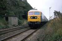 One of Stratford works characteristically painted Class 47 locomotives approaches Ardleigh level crossing at speed with a Norwich-Liverpool Street working on 25th September 1977.<br><br>[Mark Dufton 25/09/1977]