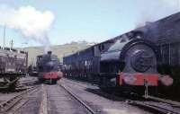 Busy scene on the harbourside at Whitehaven with two 0-4-0ST locomotives, a rake of BR coal hoppers and an NCB wooden bodied wagon. Peckett <I>Victoria</I> is on the left and a numberless and unnamed Robert Stephenson Hawthorn locomotive, believed to date from 1942 and to have been owned by the local Haig Colliery, is on the right. The houses in the background still overlook the harbour and the retaining wall is still there but, although it was busy for some time after 1968, the coal traffic and the rails are now long gone. (Thanks to Chris Gomersall and Bill Jamieson for additional information).<br><br>[David Hindle //1968]