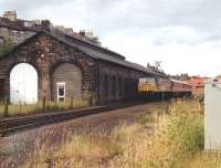 47566 with an excursion train alongside the former NER <br>
locomotive shed at Whitby (50G) in July 1993. Closed by BR in 1959 the shed is seen here in use as a ship's chandler. <br><br>[David Pesterfield 03/07/1993]