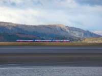 A view across the Kent Estuary to the South Lakeland Fells from Arnside village as a Barrow to Manchester Airport TPE service runs along the causeway towards the viaduct. [Photo by John Spencer]<br><br>[Mark Bartlett Collection 09/02/2010]