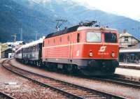 An OBB class 1044 electric locomotive takes the 1997 version of the <I>Orient Express</I> away from the St Anton stop on its Tyrolean leg and heads for Venice. The station building is in the right background. This station was subsequently replaced by an ultra modern structure on the south bank of the Rosanna River and much of this area has since been landscaped, although the main building survives as a restaurant [see image 27900].<br><br>[John Furnevel 17/07/1997]