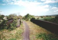 Among the confusion of lines crossing this area was a freight-only route from Niddrie West Junction to the ECML facing east, joining it near the current Musselburgh station. It ran side-by-side with other lines for most of it's length, being unaccompanied only through the village of Newcraighall. The trackbed of that section is pictured here, looking east over Newcraighall Road in May 1995. The line was superseded in the 1960s by a less direct route through the new Millerhill Yard to Monktonhall Junction.<br>
<br><br>[David Panton /05/1995]