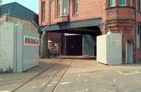 The Caledonia works of Andrew Barclay & Sons Co (later Hunslet Barclay) were located to the south of West Langlands Street and were reached by a level crossing. Note the three rails crossing the road! This 1989 view looks south over the level crossing to the entry to the works. This building remains today but given over to other uses. [See image 39875]<br><br>[Ewan Crawford //1989]