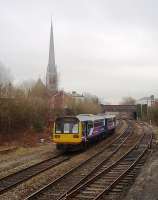 The 309' spire of St Walburge's Church, Preston (the third highest in the country) was a feature of many steam age photos of trains approaching Preston station from the north or from Blackpool. The lineside is far less accessible these days and the full spire can only really be included in pictures of the Blackpool line. In this view from St. Mark's Rd, Northern Pacer 142046 is approaching the junction with the WCML on a Blackpool South to Colne service.<br><br>[Mark Bartlett 25/03/2010]