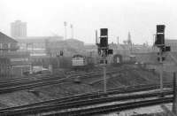 Saltley, always a busy spot, sees a Class 25 banking a coal hopper train up towards the Camp Hill line as a Brush Class 31 takes a passenger train from Norwich round towards New Street. Above the Sulzer Type 2 the flood lights of Birmingham City football ground can be seen.<br><br>[Mark Bartlett 21/01/1981]