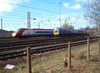 Pendolino 390012 is stabled on an electrified siding outside Preston power box (built on the site of Preston steam shed) in between London trips. The line to Lancaster (going off to the right) was closed for weekend engineering so Virgin services turned back here. TPE 185142 leaves the Blackpool line to run into Preston station on its way to Manchester Airport. The ramshackle looking fence posts in the foreground have been replaced by a substantial fence a few feet further away from the line.<br><br>[Mark Bartlett 27/03/2010]