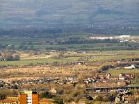 A Class 334 unit running along the embankment next to the M8 directly opposite Glasgow Airport with a service for Gourock. In the bottom right hand corner of shot is railway viaduct at Ferguslie carrying the Glasgow, Paisley, Kilmarnock and Ayr Railway. In the centre bottom of shot is Ferguslie Station on the Paisley & Barrhead District Railway, with the line of trees that runs to the centre right showing the trackbed of the PBDR that ran to Paisley St. James. The housing at the  bottom left stands on the site once occupied by the Pressed Steel plant and Chrysler car factory.<br><br>[Graham Morgan 07/04/2010]