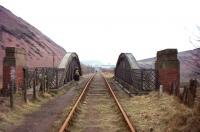 Bridge carrying a mineral line across the old A8 (now A89) south towards Uphall oil works in February 1965. The  rooftops of the works lie directly ahead with shale bings dominating the surroundings. The track and oilworks are long gone but the bridge over the A89 still stands, albeit with a new deck, having been modified to serve as a pedestrian footbridge. [See image 28643]<br>
<br><br>[Frank Spaven Collection (Courtesy David Spaven) 23/02/1965]