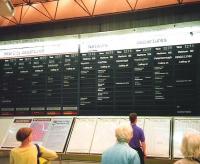 The flipover departure indicator at King's Cross on 14 July 1994. I'm not sure if this was made by Solari, the usual manufacturer of such things, as the leaves didn't flip over gently falling by gravity but zipped through at an alarming rate, a complete column appearing within 2 seconds. How this was achieved I couldn't fathom. I also can't work out whether that's a cycle helmet made to look like hair or hair made to... <br>
<br><br>[David Panton 14/07/1994]