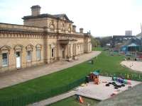 The main station building at Halifax was in a semi derelict condition for many years but has now been refurbished and incorporated into the Eureka museum complex. Behind this imposing structure the surviving island platform at Halifax is still busy with trains. The land in the foreground was once occupied by tracks leading to the LYR goods depot and the museum's preserved shunter can just be seen under the bridge [See image 28759] standing in the old yard area.<br><br>[Mark Bartlett 24/04/2010]