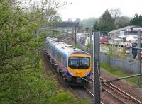 The 1400 TransPennine Manchester Airport - Edinburgh Waverley on 13 May 2010 on the WCML some 4 miles north west of Gretna about to pass the site of Kirkpatrick station. The surviving footbridge stands in the background while the former goods yard on the right now plays host to a selection of agricultural and transport items, most of which appear to have seen better days. While the village is named Kirkpatrick Fleming, the railway station (1847-1960) was plain Kirkpatrick throughout.<br><br>[John Furnevel 13/05/2010]