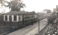 A Sentinel steam railcar calls at Burgh-by-Sands on a Port Carlisle branch service around 1930, with Station Master Walter Tait posing alongside on the platform. The Sentinel is thought to be no 31 'Flower of Yarrow', which was built in 1928 and operated on the Port Carlisle branch up to the time the branch was closed from Drumburgh in 1932, although being on the 'main line' Burgh-by-Sands kept going until 1964.<br><br>[Bruce McCartney Collection //]