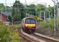 320321 heads west from Cardross on 29 May 2010 with a service to Helensburgh Central. Compare with the photograph taken from almost the same spot in the mid 1970s [see image 11104]. The OHLE position and type of structure does help to position the shot. The entire goods yard has now been built on and the large green building in the sawmill blocks the view of the station footbridge.<br>
<br><br>[John McIntyre 29/05/2010]