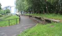 Miraculous survivor. The Edinburgh - bound platform of Dalry Road station on 6 June 2010 looking towards Princes Street. Ironically the path leads to a bus stop (visible through the trees just before the end of the platform) located in a lay-by alongside the Western Approach Road, from which buses now carry passengers on the short hop (600m) to Princes Street along the trackbed of the former railway. Dalry Road shed stood just off to the right of the photograph. [See image 29251]<br><br>[John Furnevel 06/06/2010]