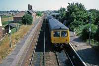 In 1983, before the construction of the direct line from Felixstowe docks to Trimley, the up platform at Trimley was still in use for passengers. An Ipswich-bound DMU has just crossed another bound for Felixstowe Town. Passengers on this platform had to be alert to the signalman cycling back and forth to operate the crossing gates.<br><br>[Mark Dufton 30/07/1983]