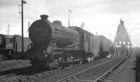 Sunshine and steam in the shed yard at Thornton Junction in the 1960s. J38 no 65911 takes centre stage with Austerity 90444 standing over on the left. Both were Thornton locomotives and both were withdrawn in the first quarter of 1967, just before the official closure to steam of 62A itself. Beyond the coaling plant in the right background the curved roof of <I>The snake pit</I> can be seen [see image 23695]. <br><br>[K A Gray //]